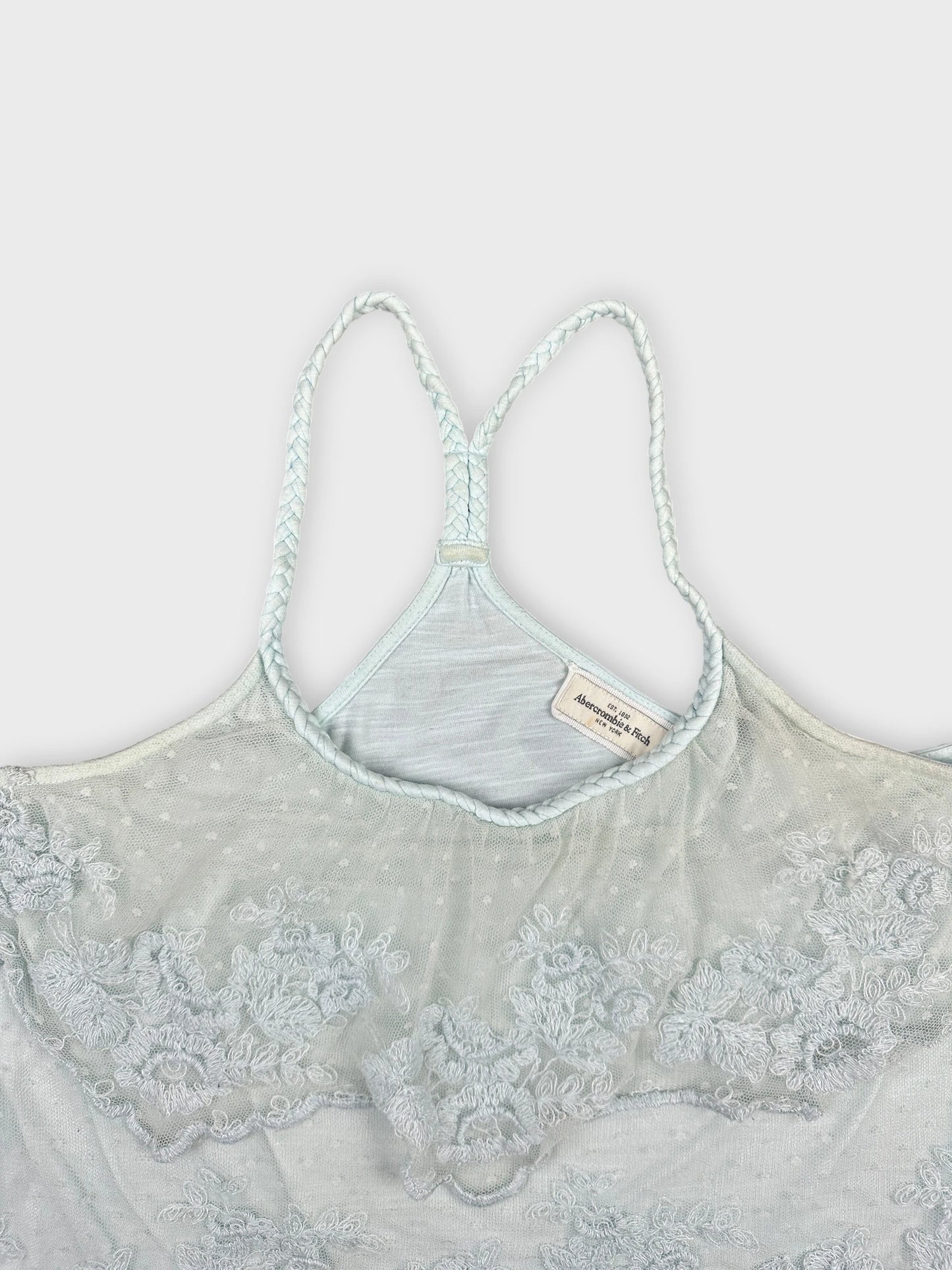 detail view of a light blue women's top featuring floral lace trim