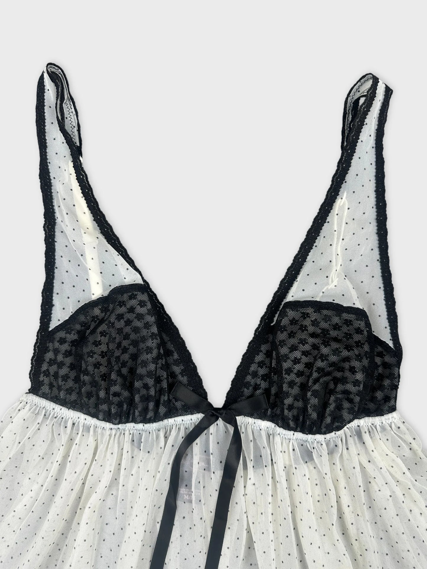 Detail view of a vintage white top with black polka dots and lace trim.