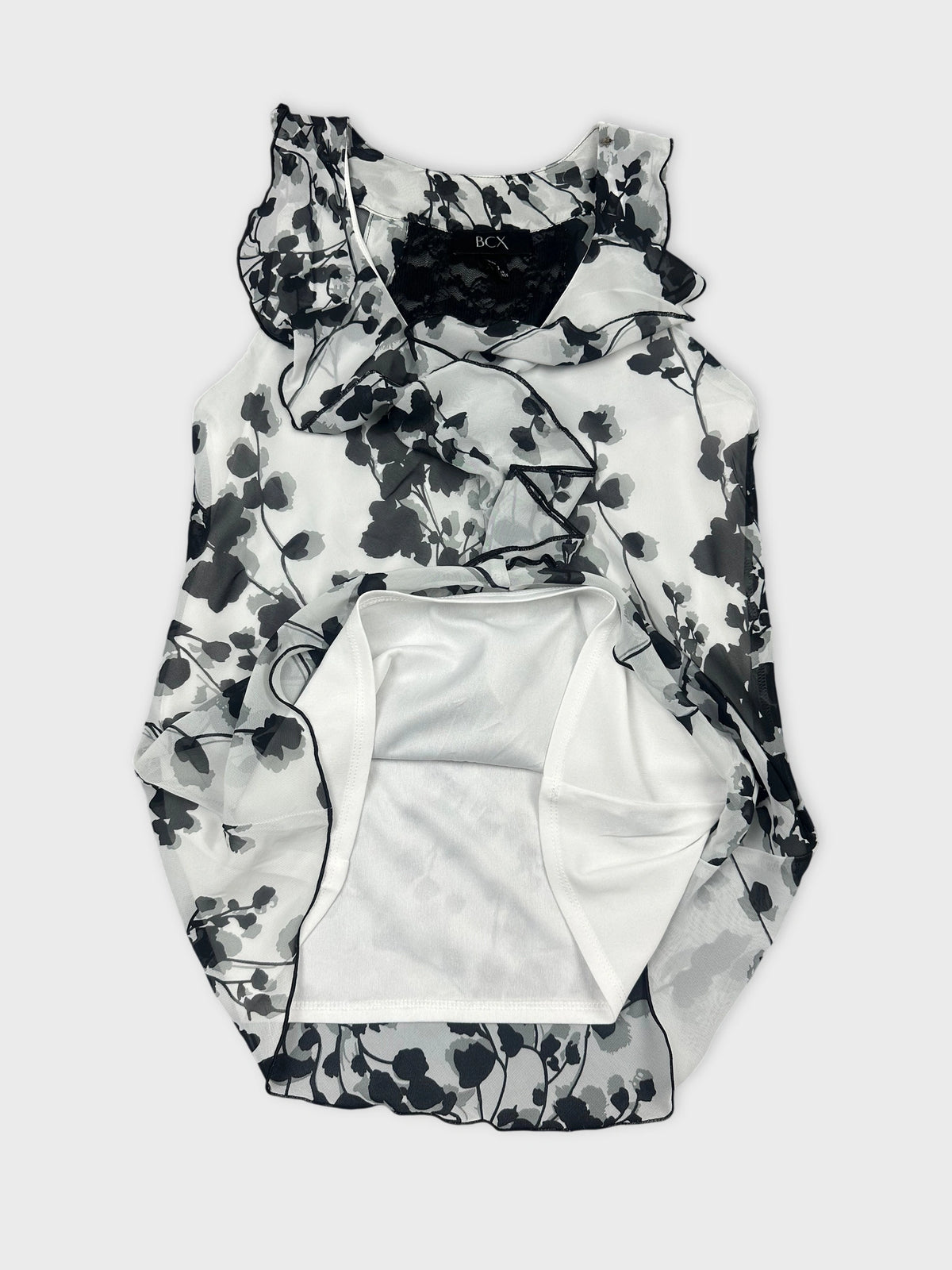 Detail view of a black and white floral ruffled tank top.