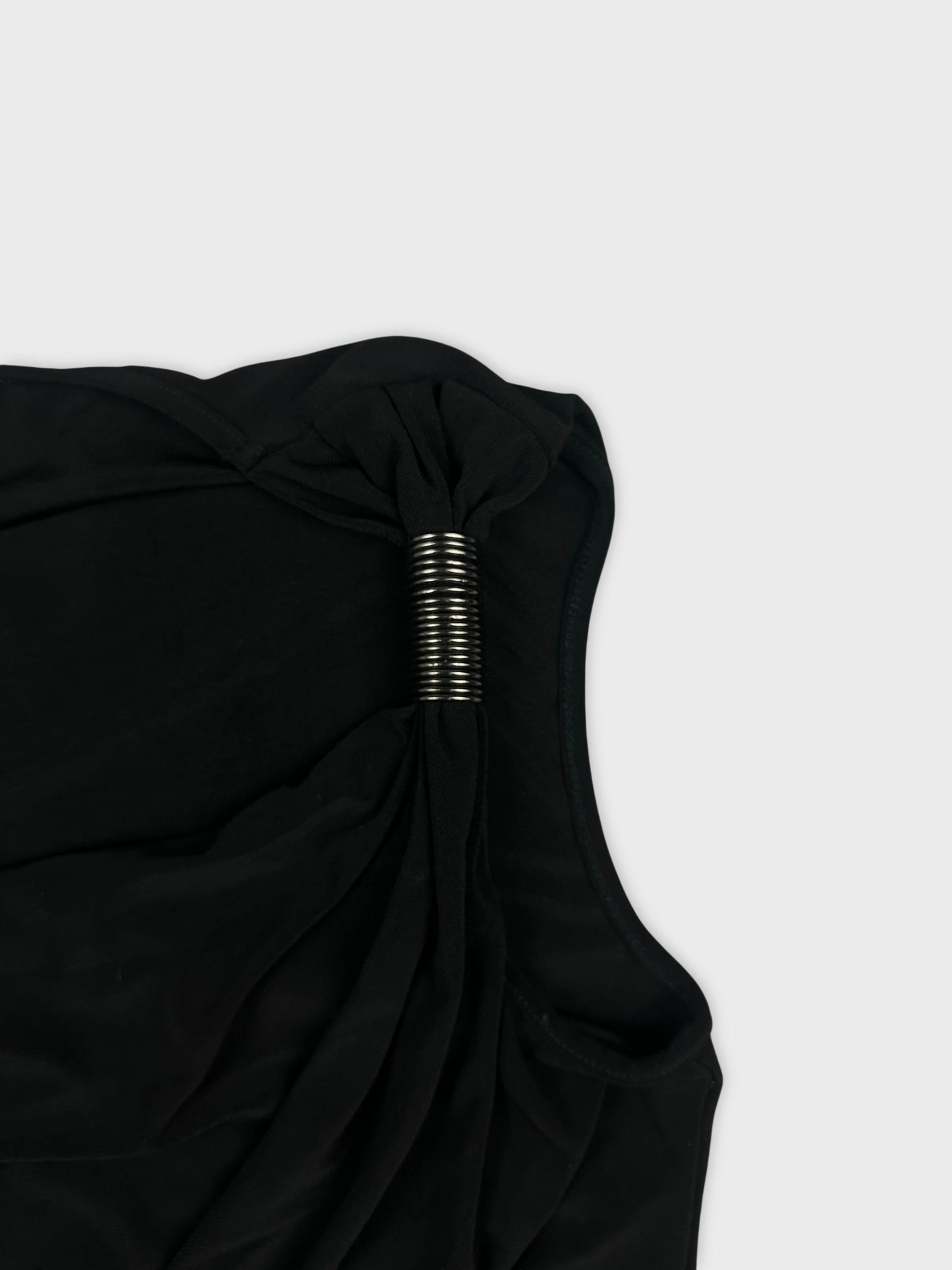 Detail view of a black top featuring a twisted design and metallic accent.