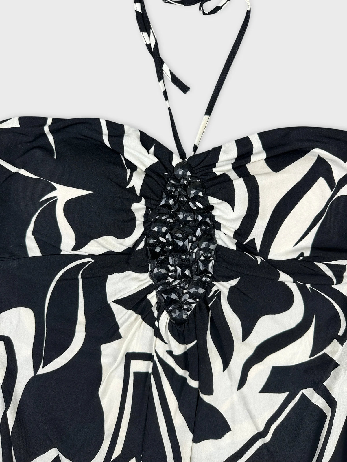 Detail view of a black and white patterned top with beaded embellishment.
