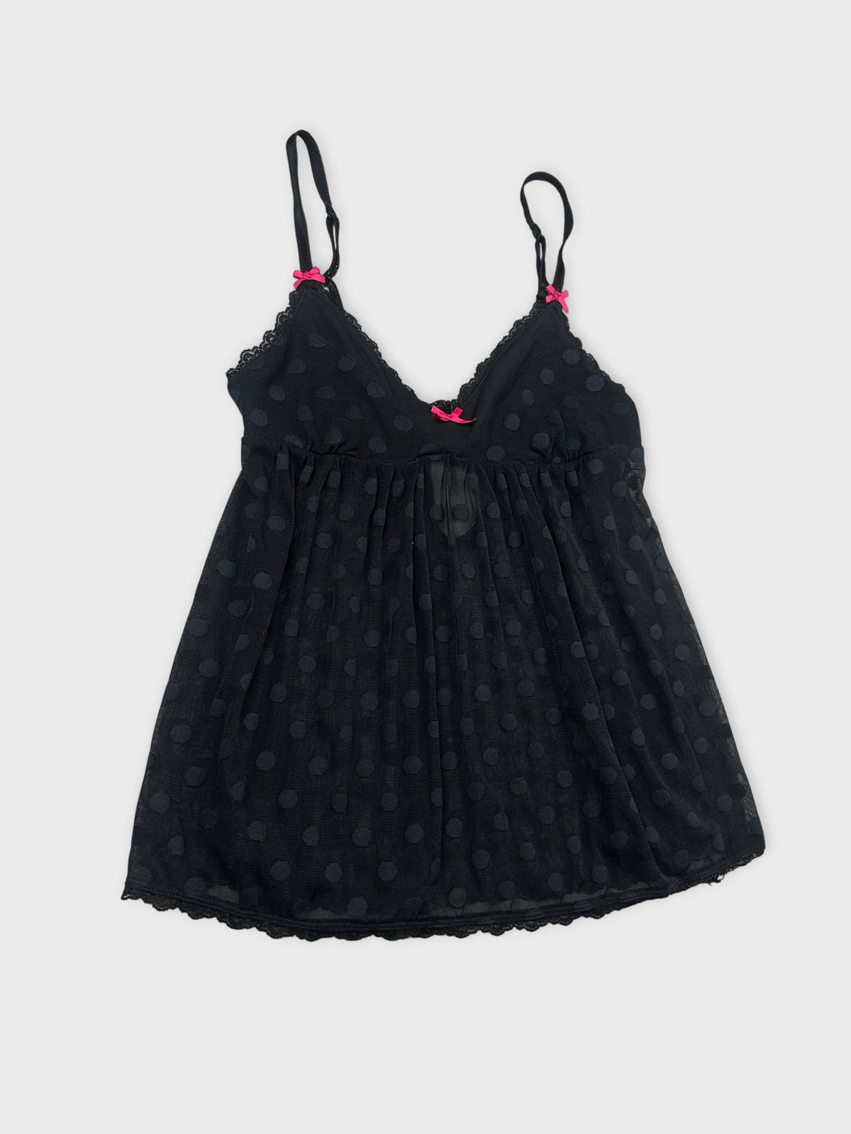 Detail view of a black polka dot camisole with pink straps.
