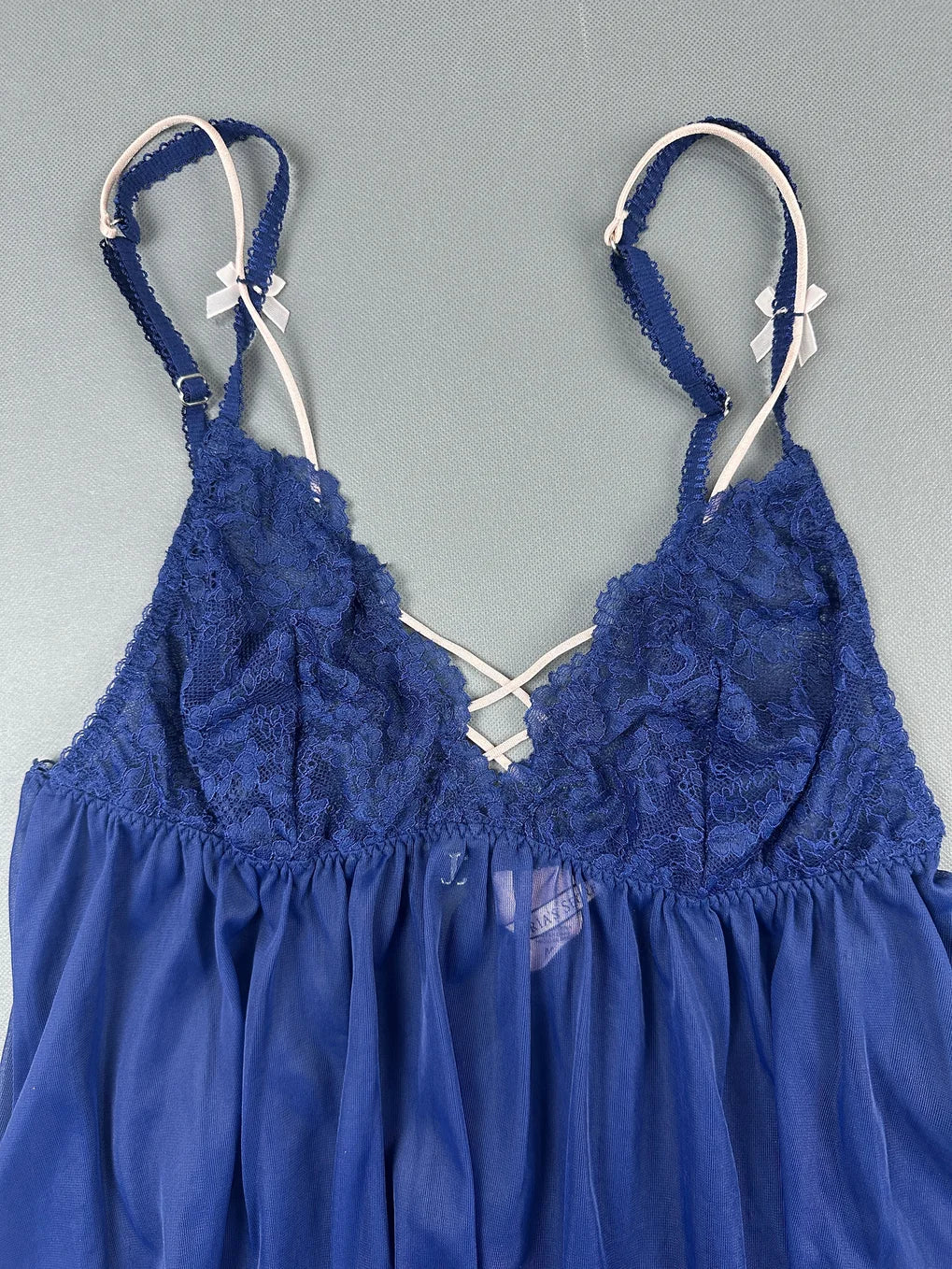 Detail view of a blue lace top with adjustable straps and soft pleats.
