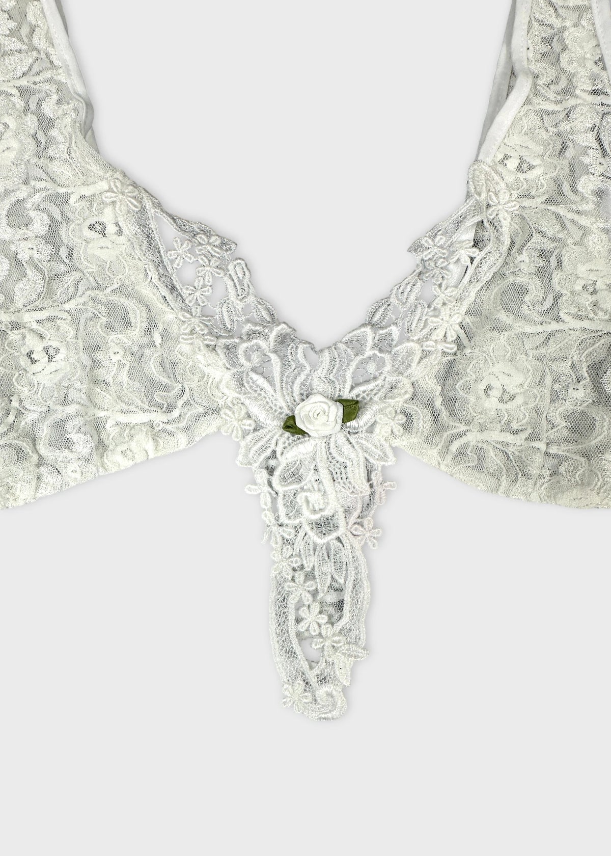 Detail view of a white lace top with floral embroidery.
