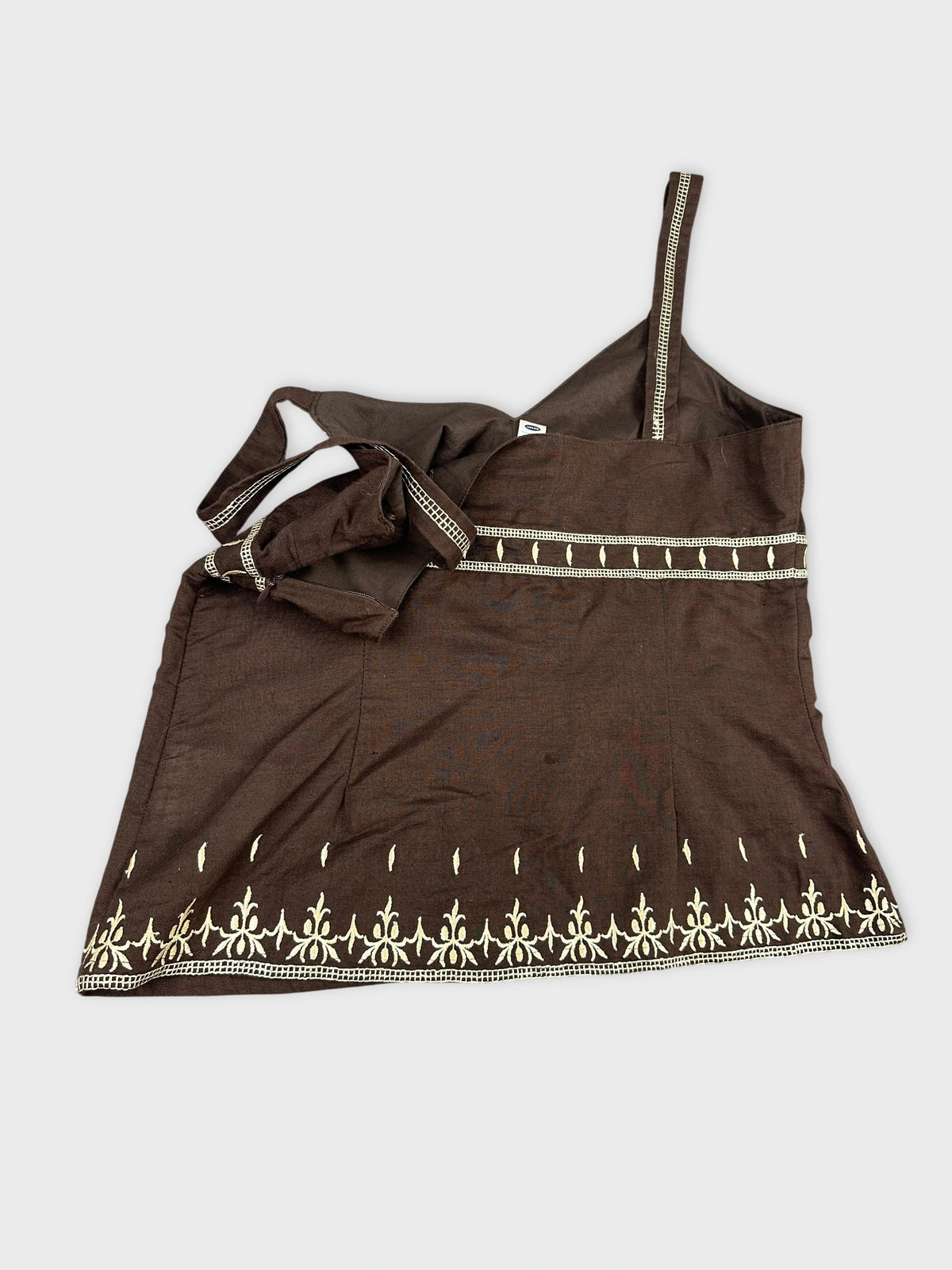 detail view of a brown women’s upper body top with white embroidered pattern