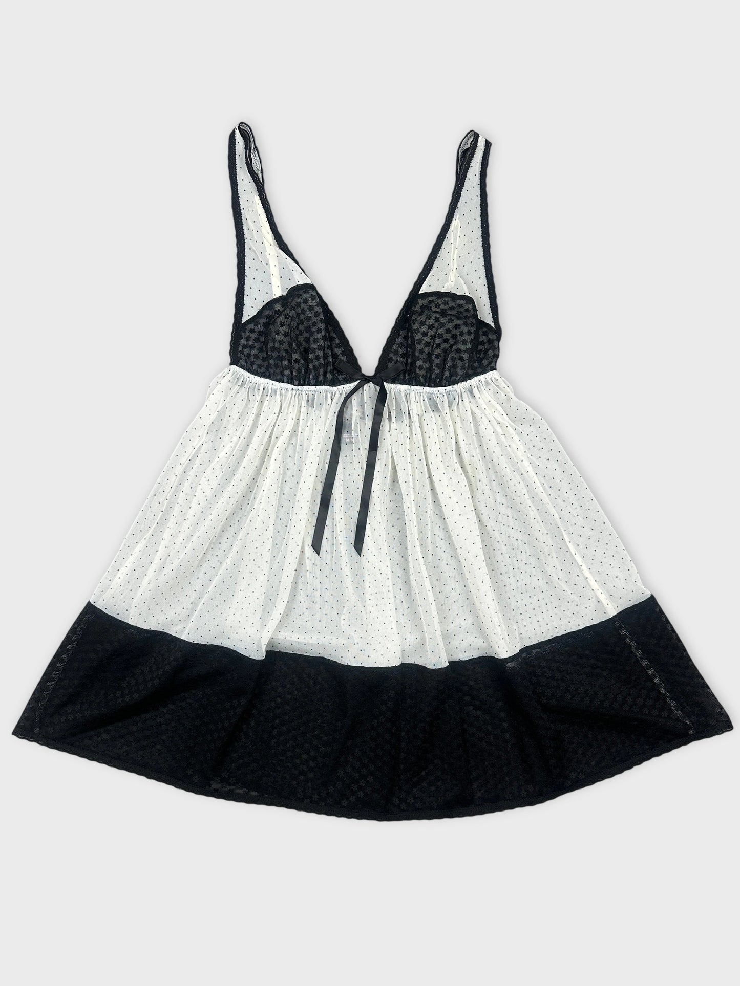 Front view of a black and white polka dot top with a tie detail.