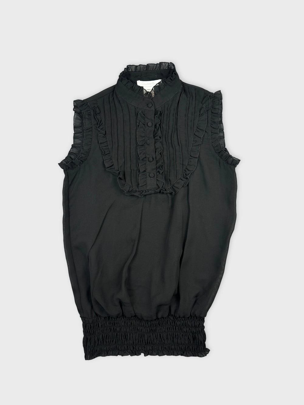 Front view of a black vintage top with ruffled trim and button details.