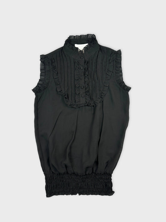 Front view of a black vintage top with ruffled trim and button details.