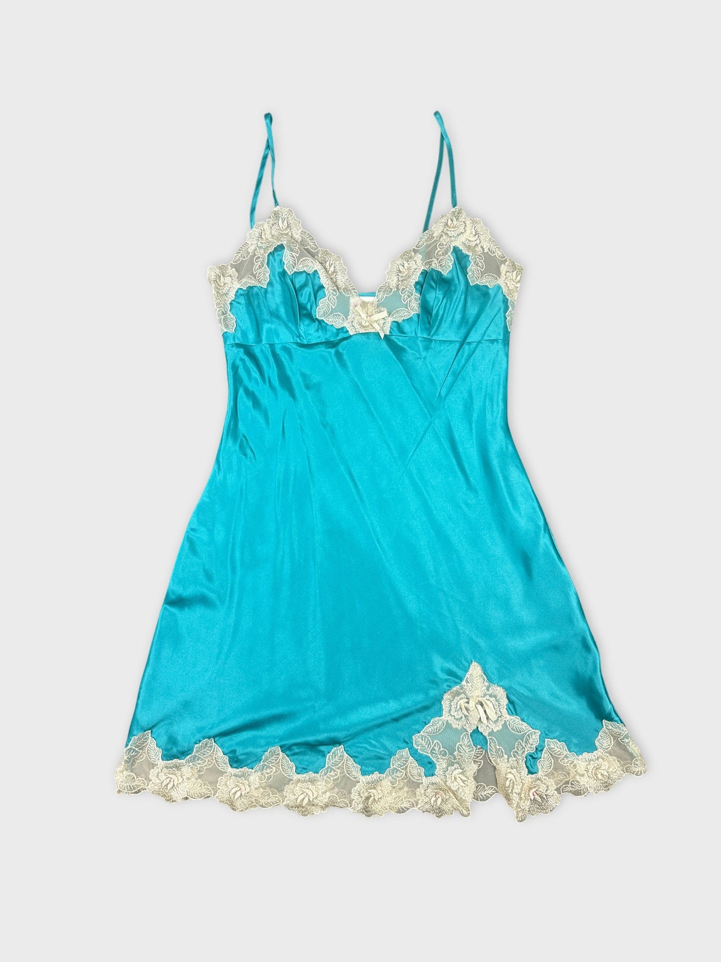 Front view of a turquoise slip top with floral lace trim.