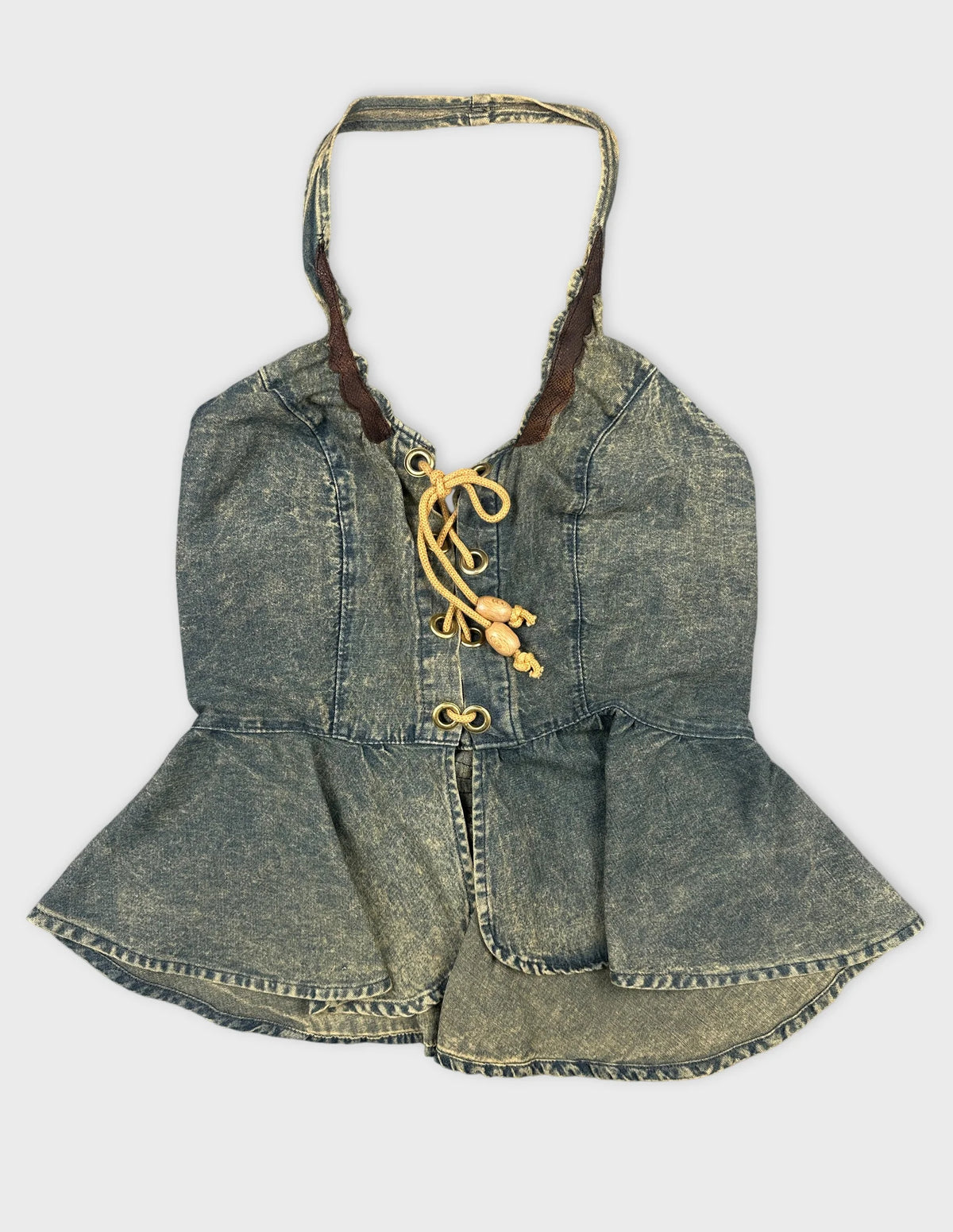 Front view of a denim peplum top with lace-up detail.