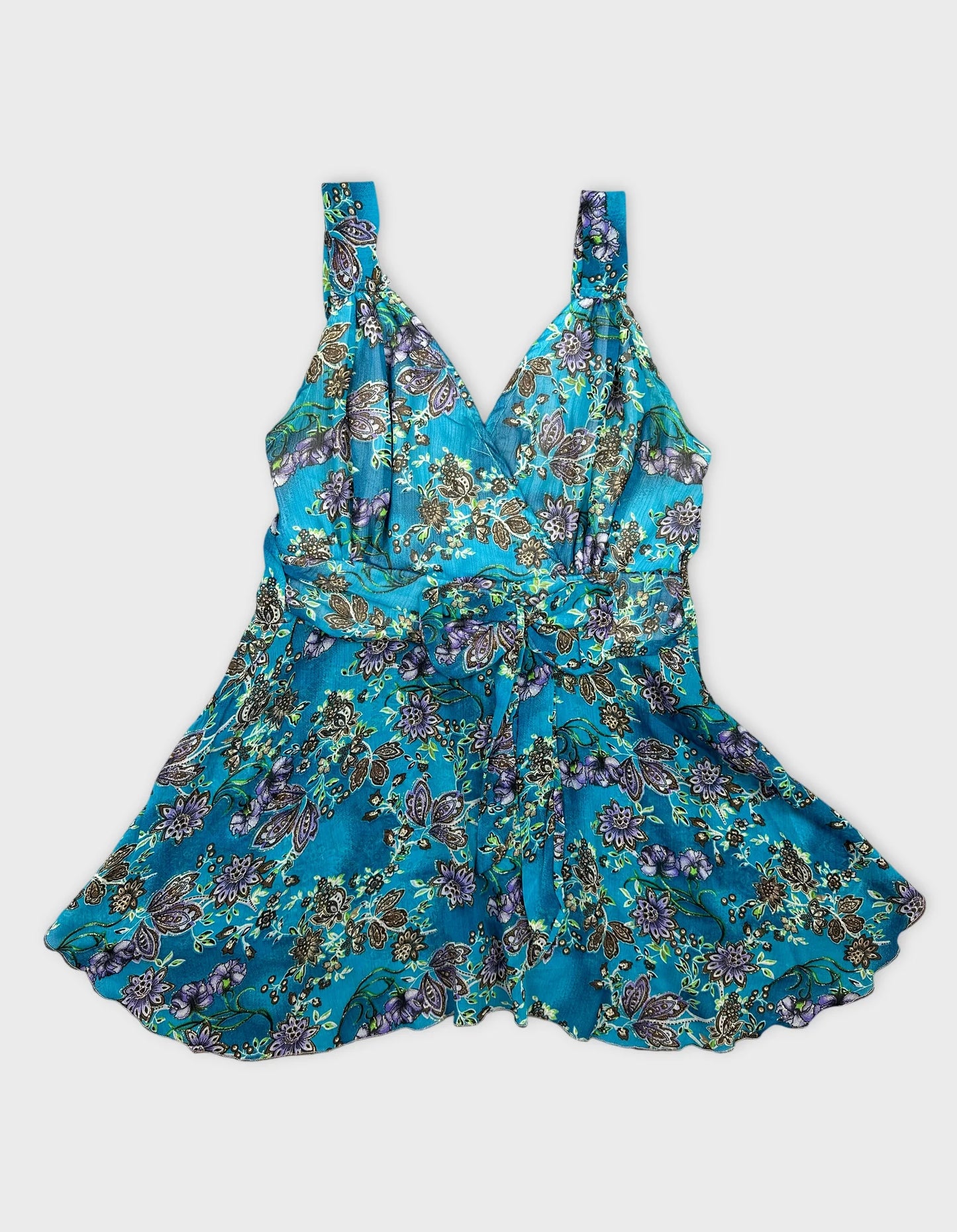 Front view of a sleeveless blue floral top with a wrap shape.