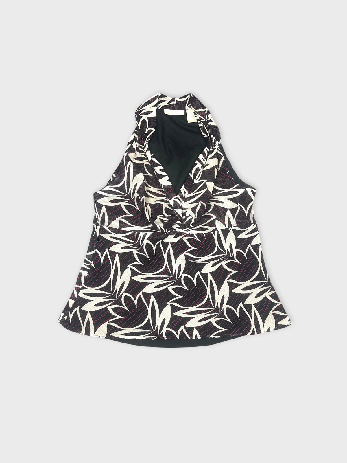 Front view of a black and white floral sleeveless top with a draped neckline.