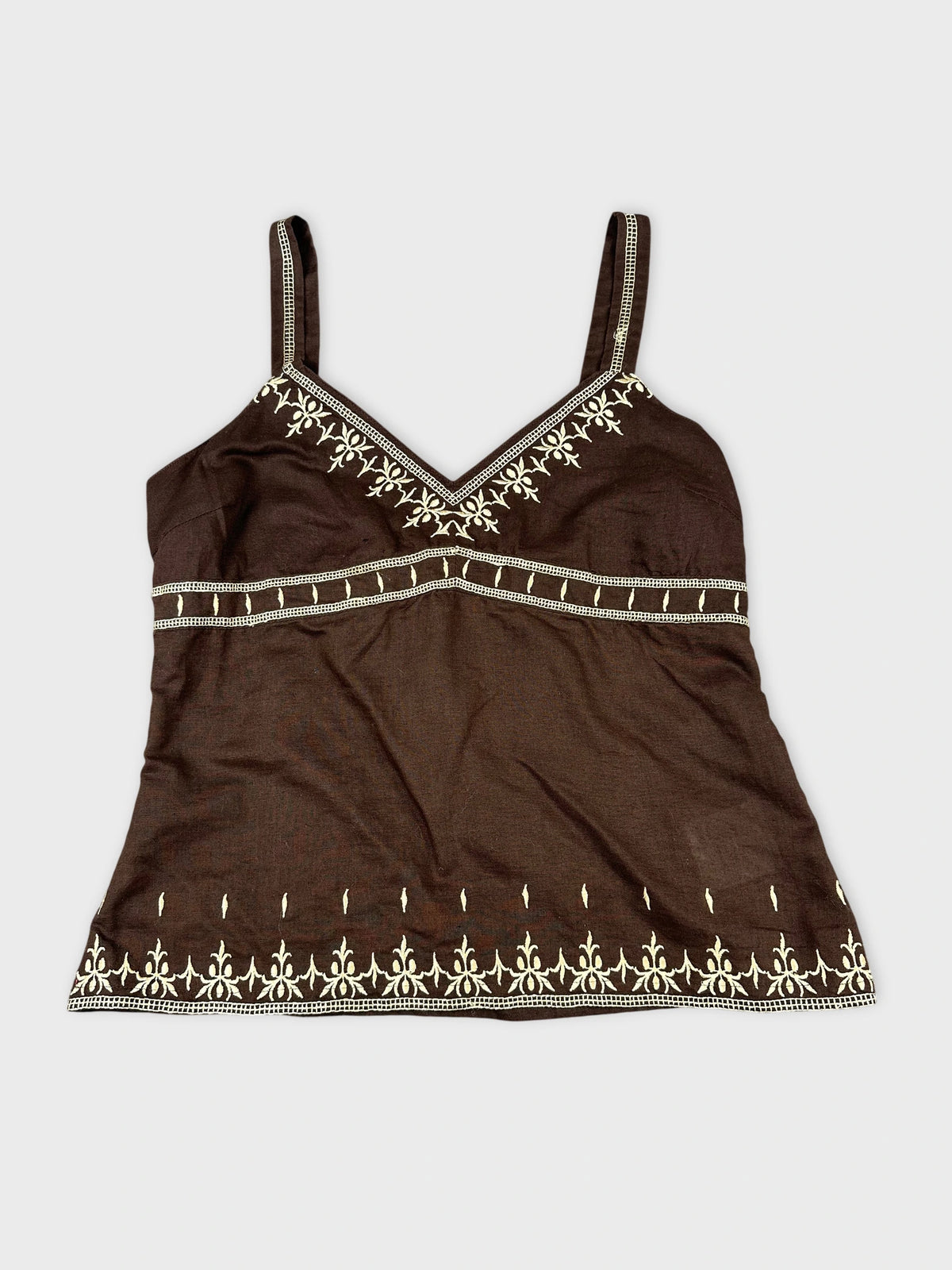 Front view of a brown top with white embroidered designs.