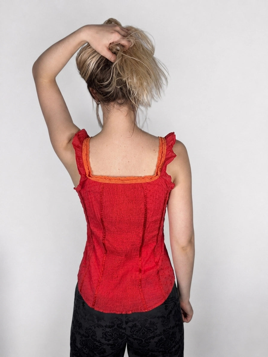 Back view of a red women's top featuring ruffled straps and textured fabric.