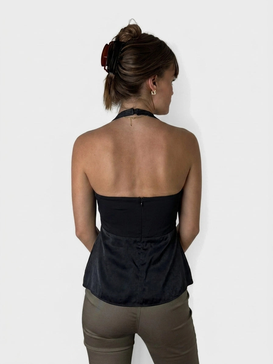 Back view of a black peplum top featuring a zip closure.