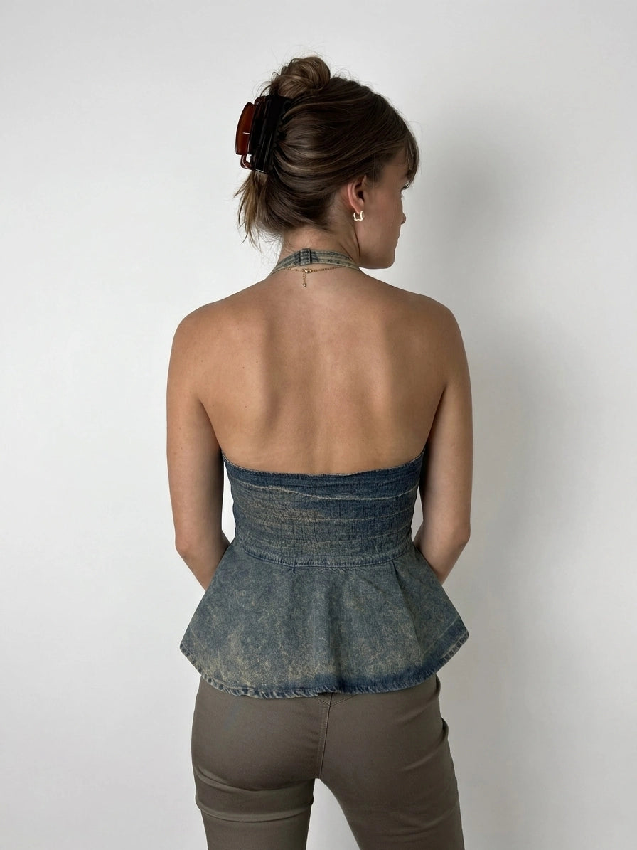 Back view of a denim peplum top with a faded blue color.
