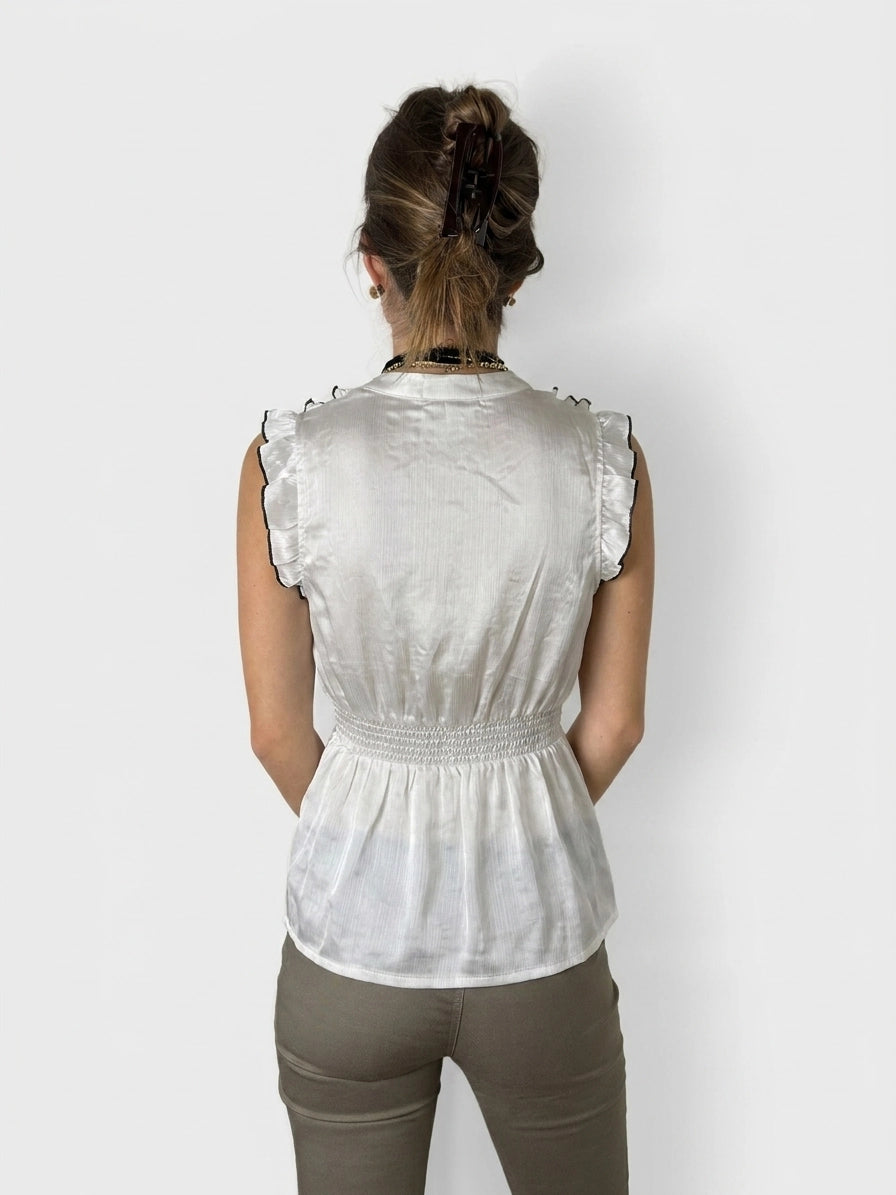 Back view of a cream upper body top with ruffled trim.
