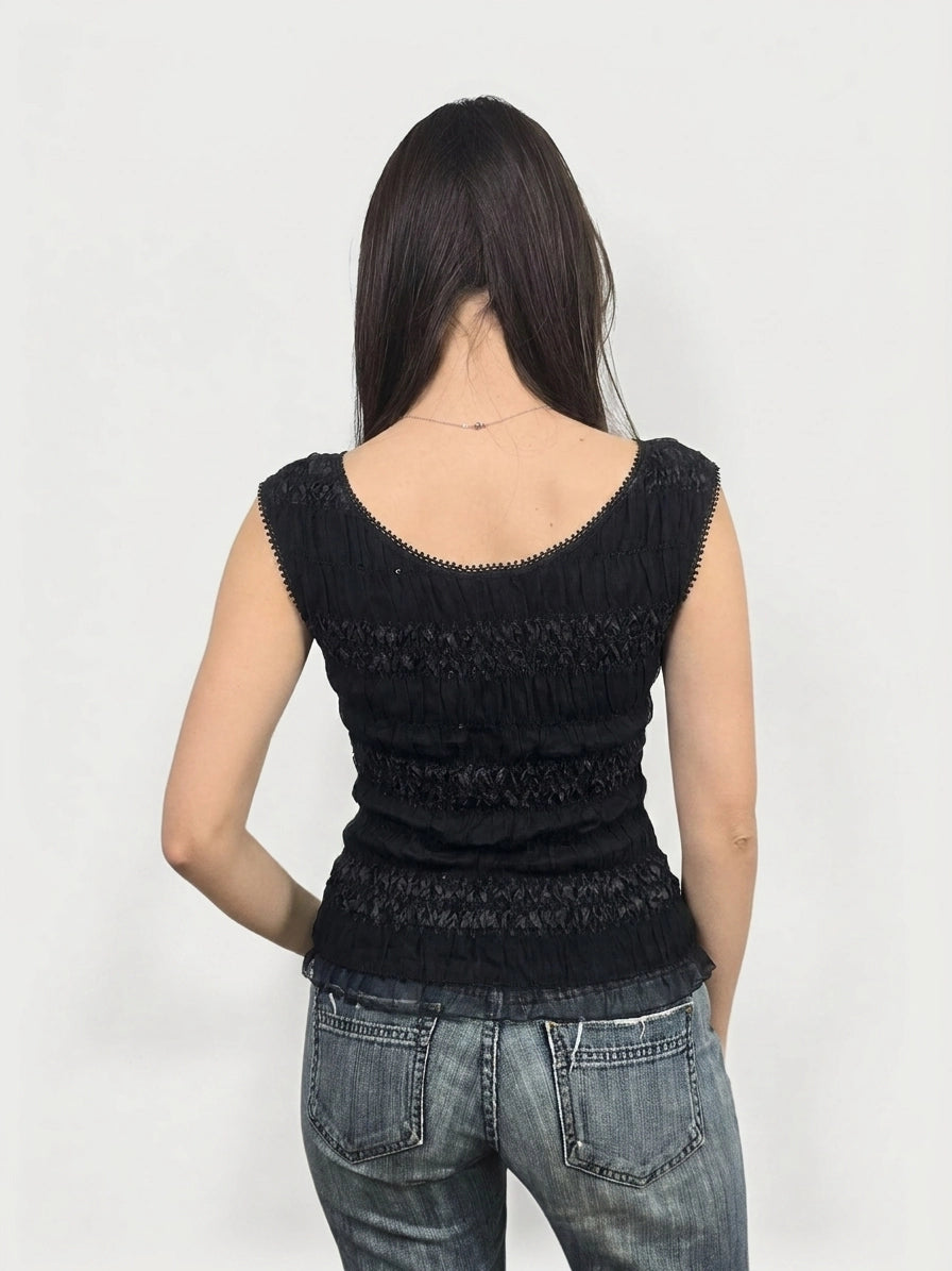 Black smocked top with lace trim, back view of garment worn by model.