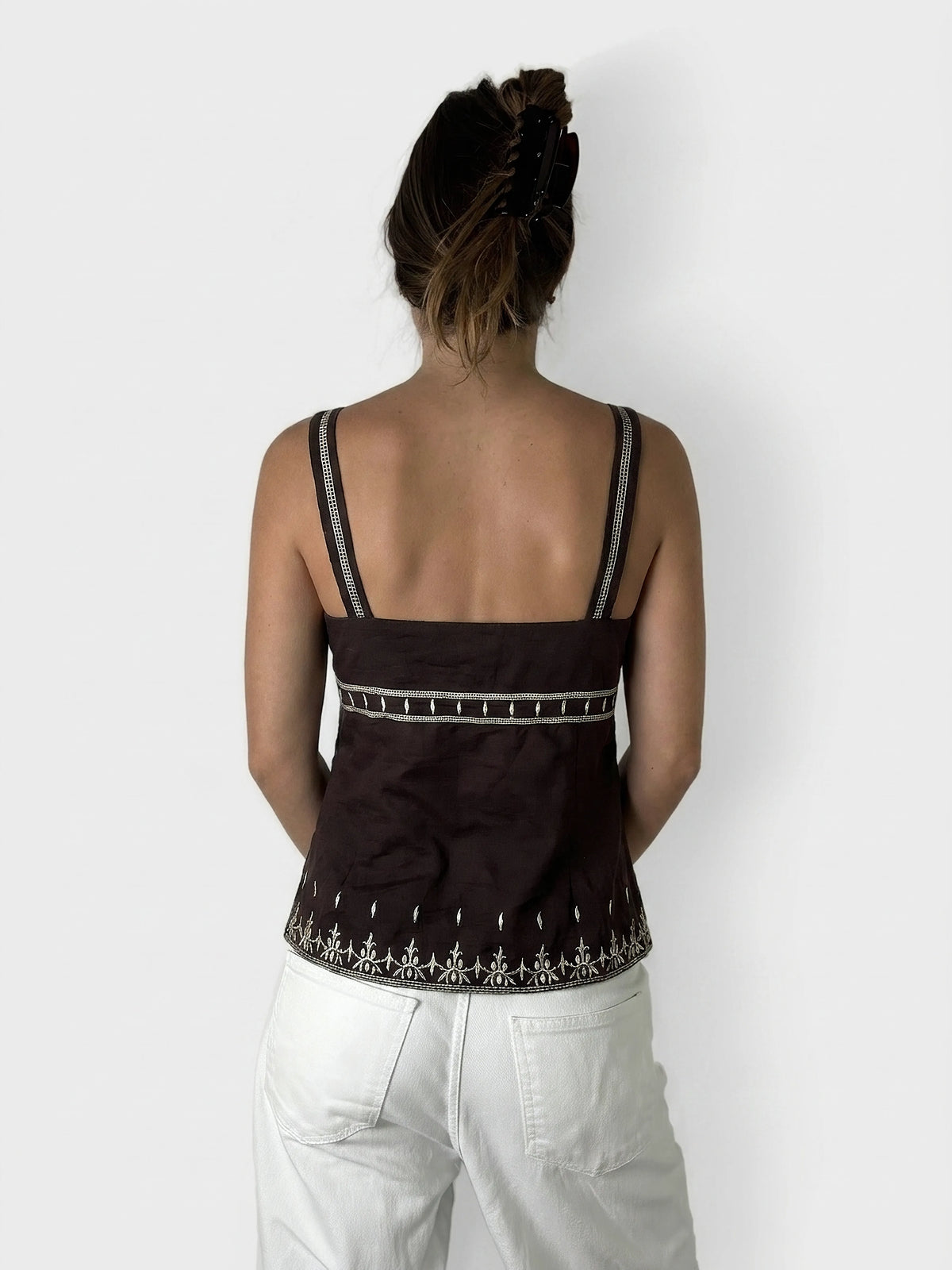 Back view of a brown upper body top with embroidered trim.