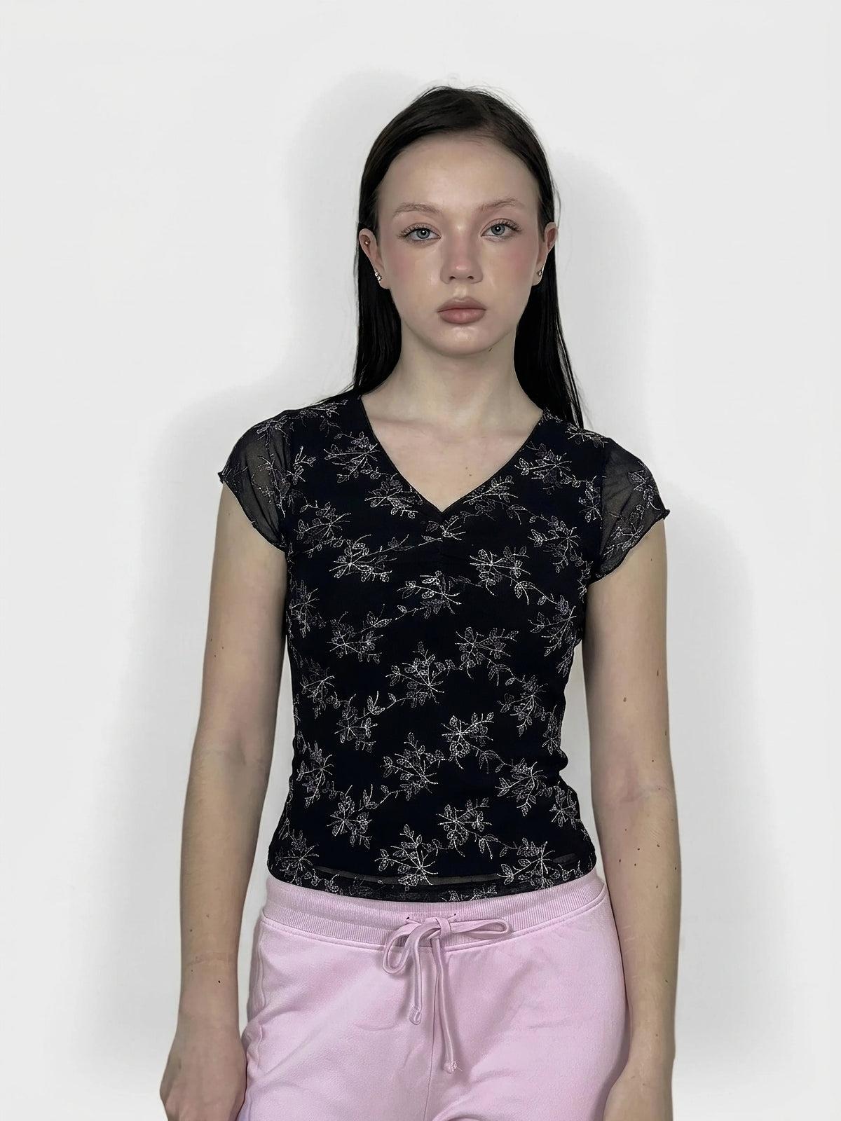Women's upper body top in black with floral print, front view.