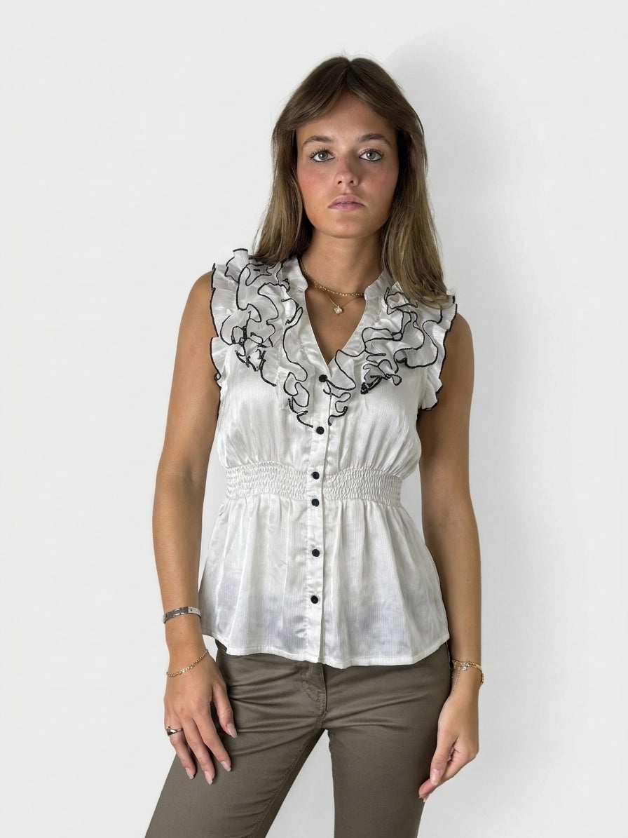 Front view of a white vintage top with ruffled collar and black trim.