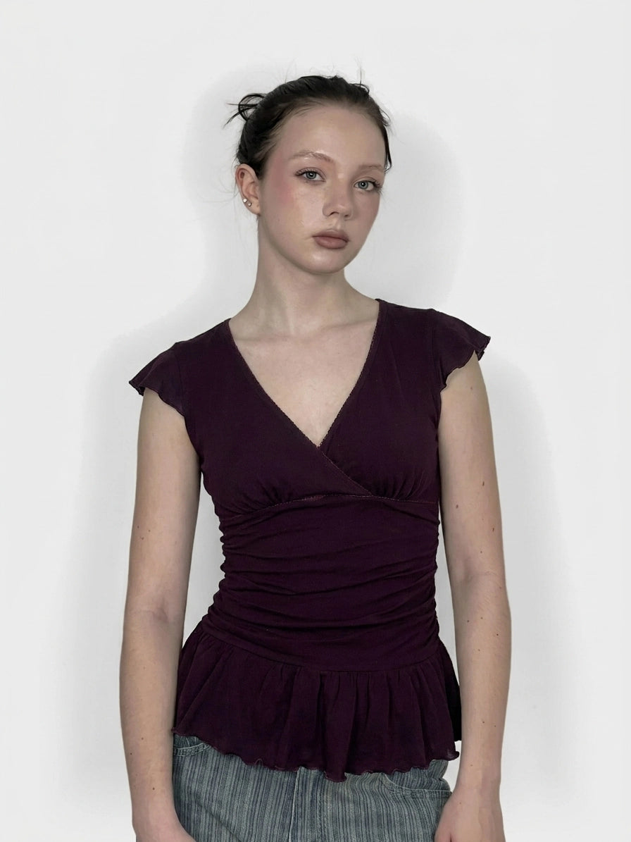 Front view of a purple peplum top with short sleeves and a v-neck.