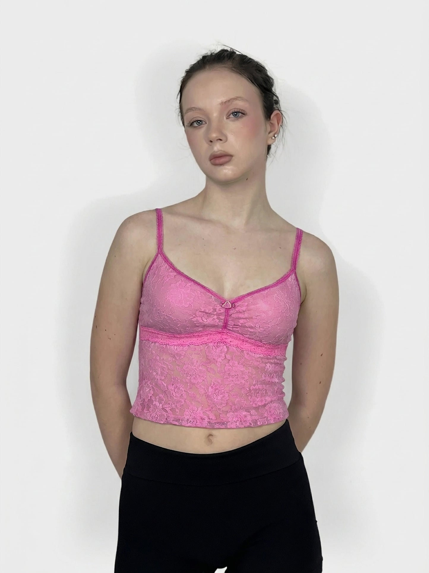 Front view of a pink lace crop top with thin straps.