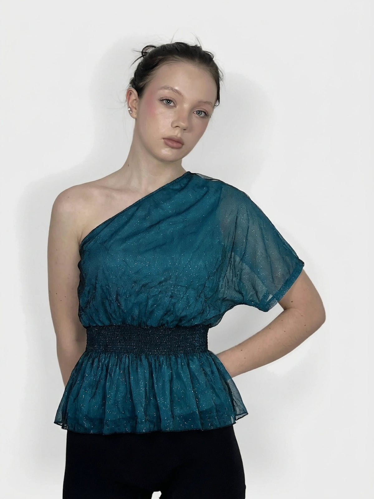 Teal women's top with peplum waist and sheer fabric, front view.