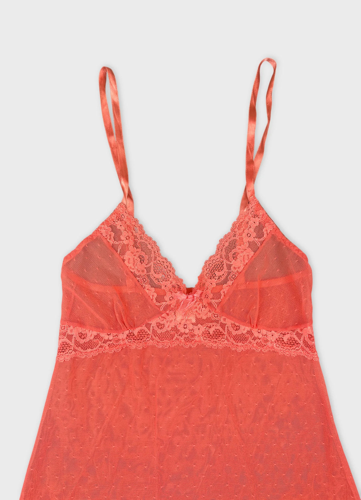 Detail view of a coral lace-trimmed camisole with thin straps.