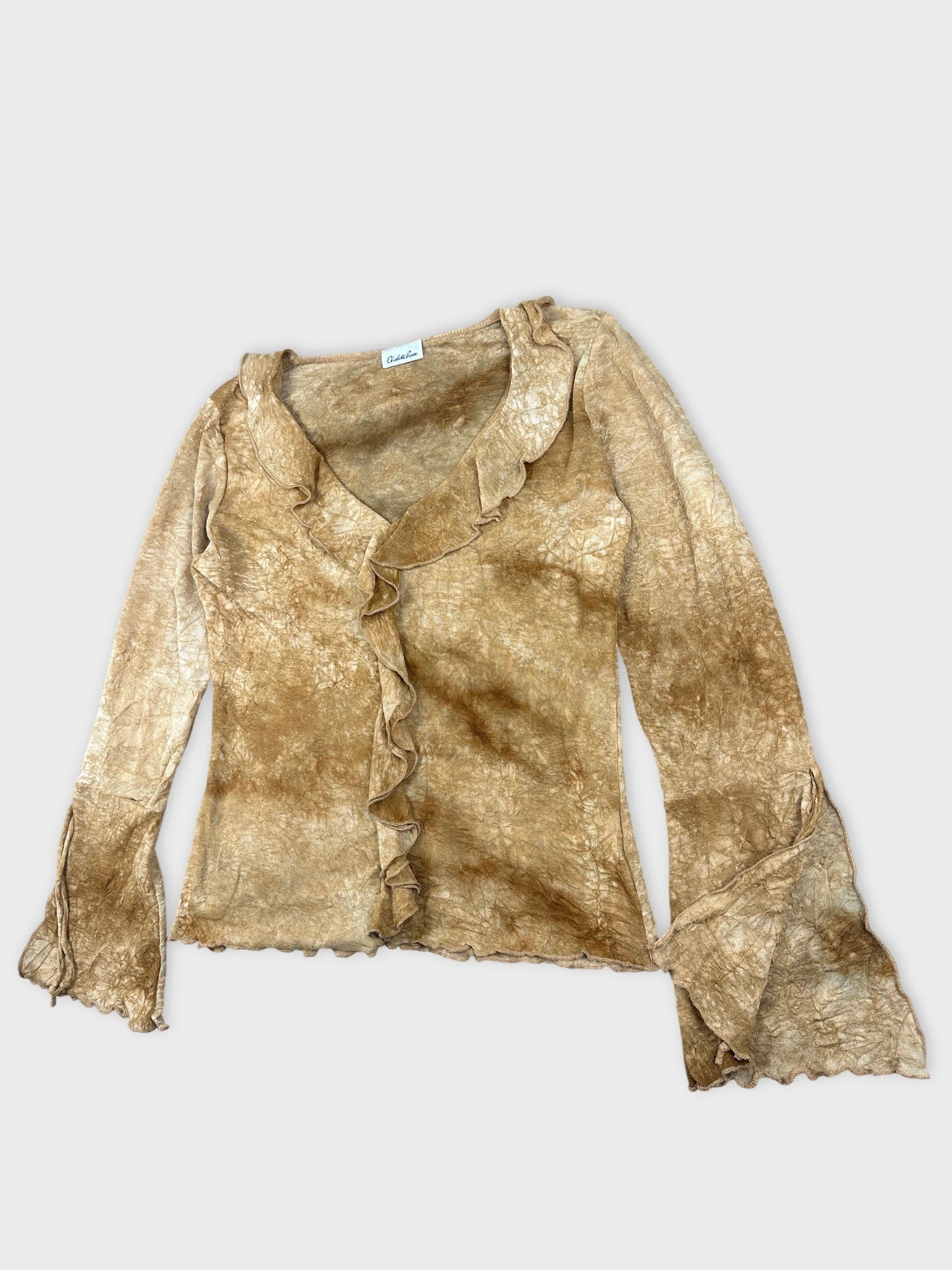 Detail view of a long sleeve women's blouse in gold with ruffled trim.