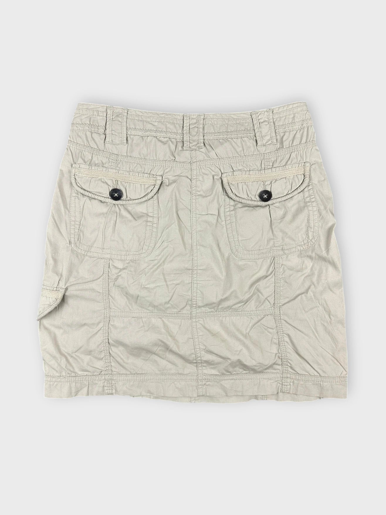 Beige mini skirt with side pockets back view showing button details.