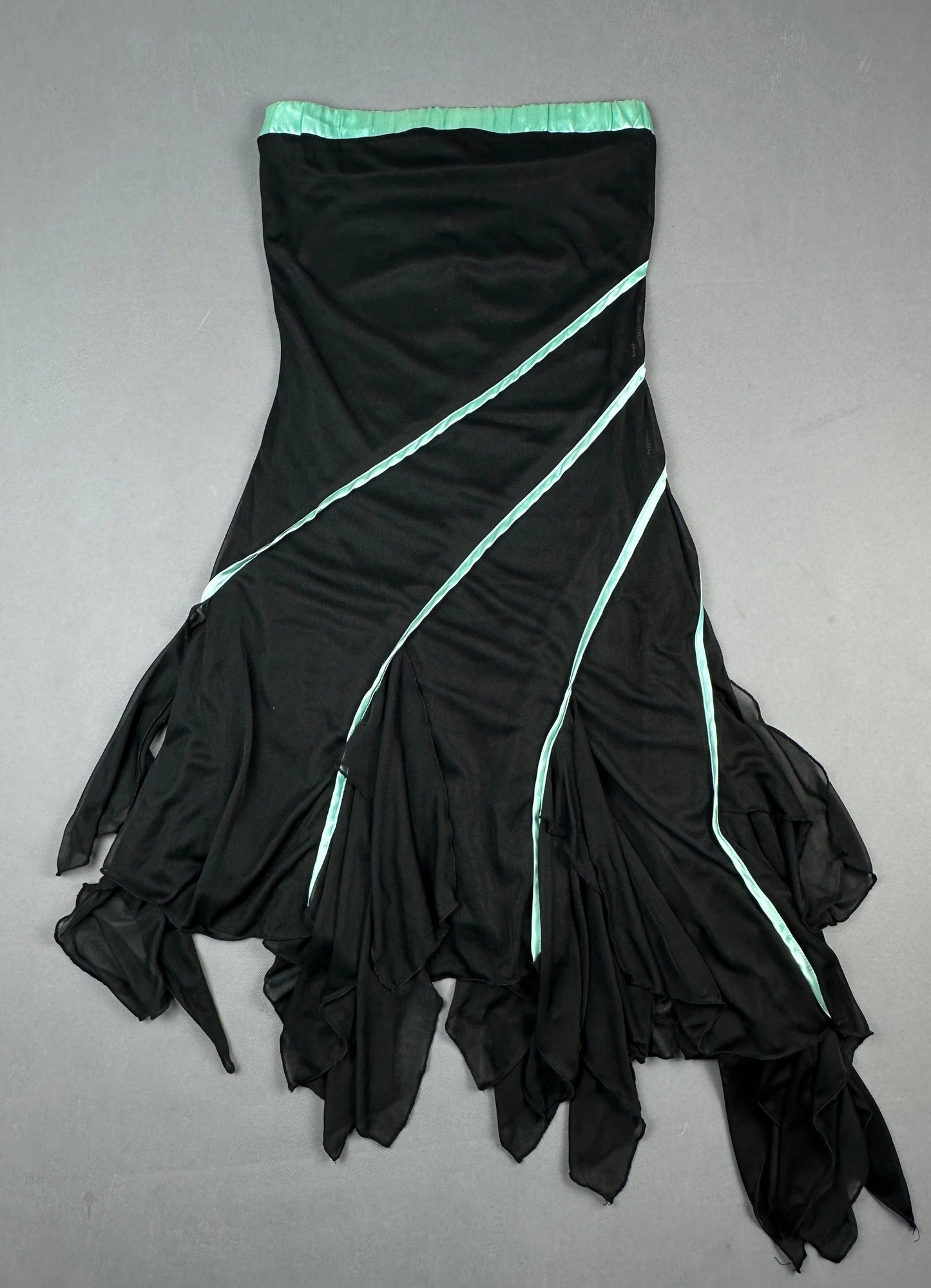 Back view of a black flowing skirt with aqua accent details and an asymmetrical silhouette.