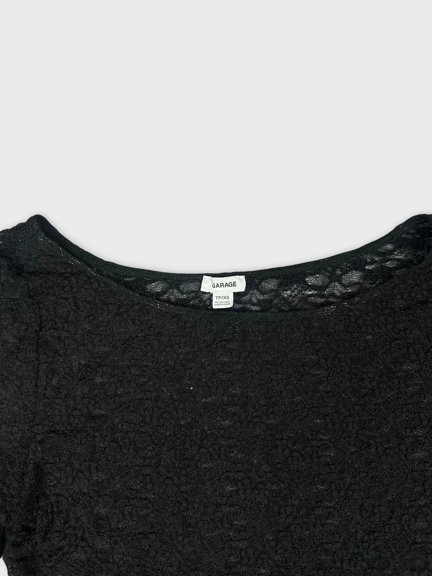Detail view of a black lace long sleeve top with a rounded neckline.