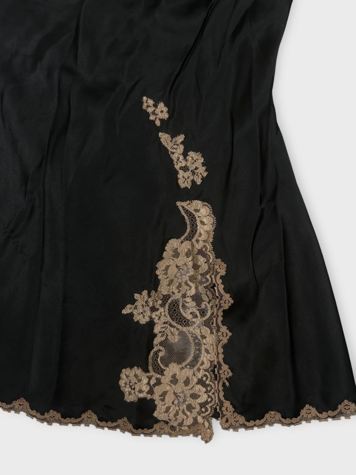 Black lace trimmed cami top detail view with floral pattern embellishments.