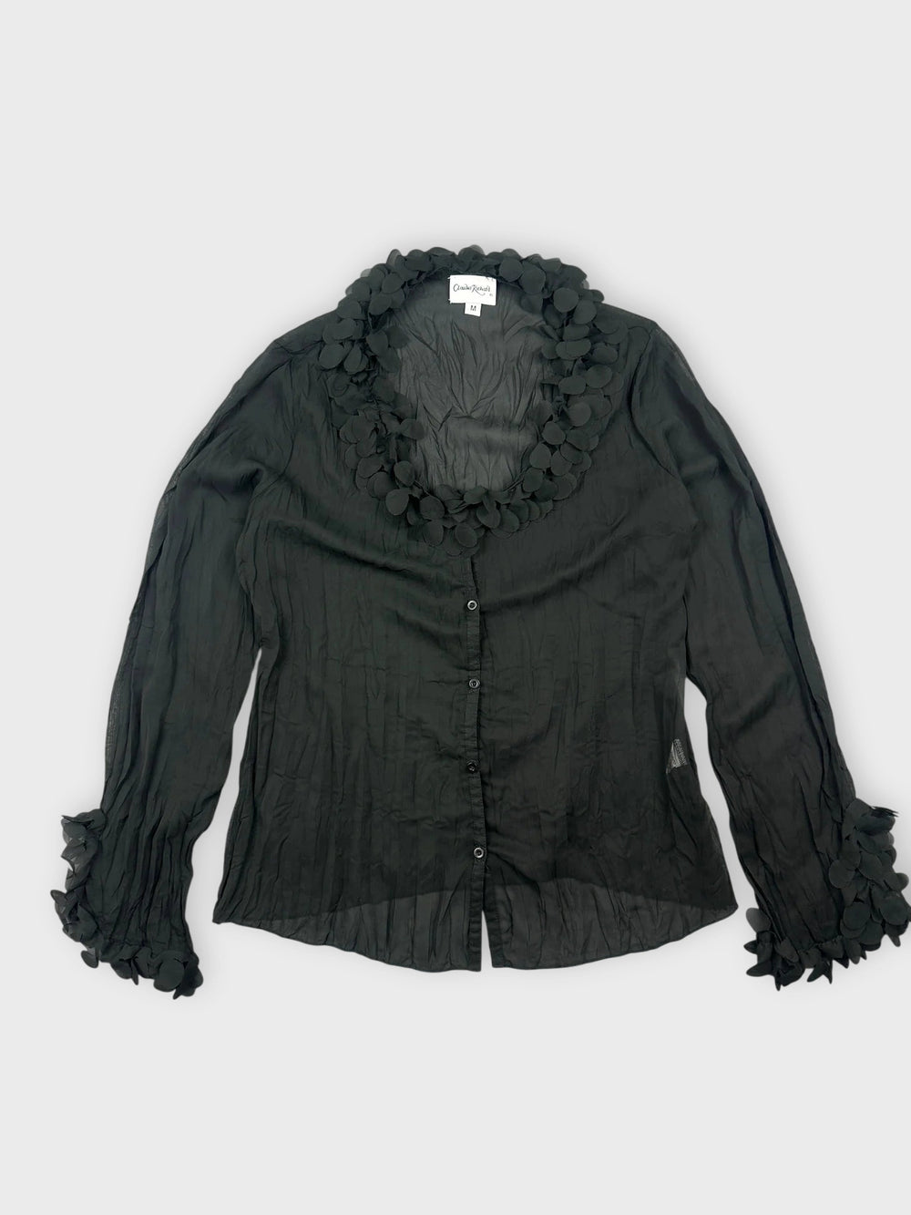 Front view of a black long sleeve shirt with floral trim on collar and sleeves.
