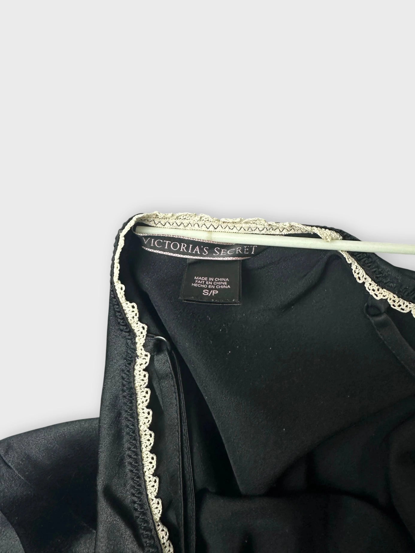 Detail view of black satin cami featuring white lace trim.
