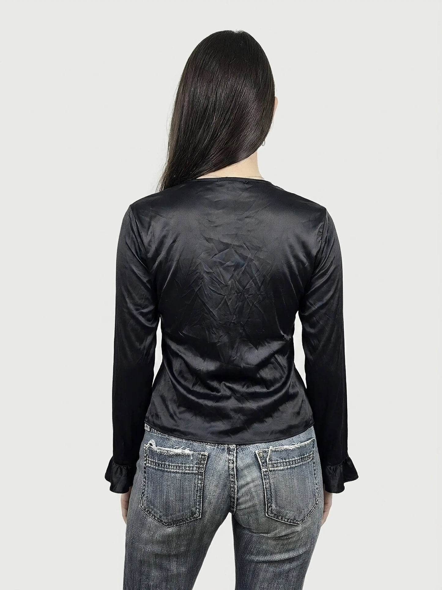 Back view of a black silk ruffled top with long sleeves.