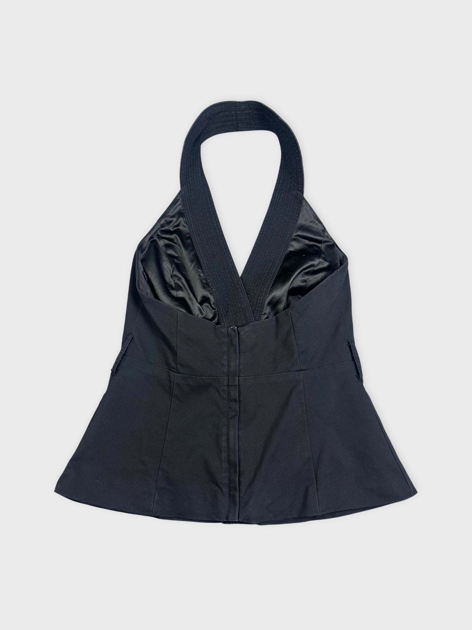 Back view of a black sleeveless blazer vest featuring a flared hem.