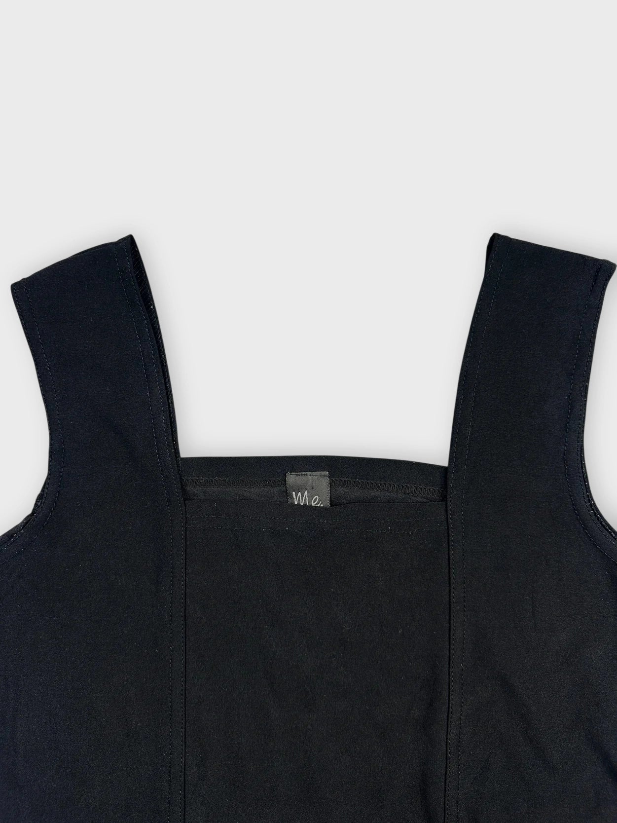Black sleeveless top detail view featuring a square neck design.