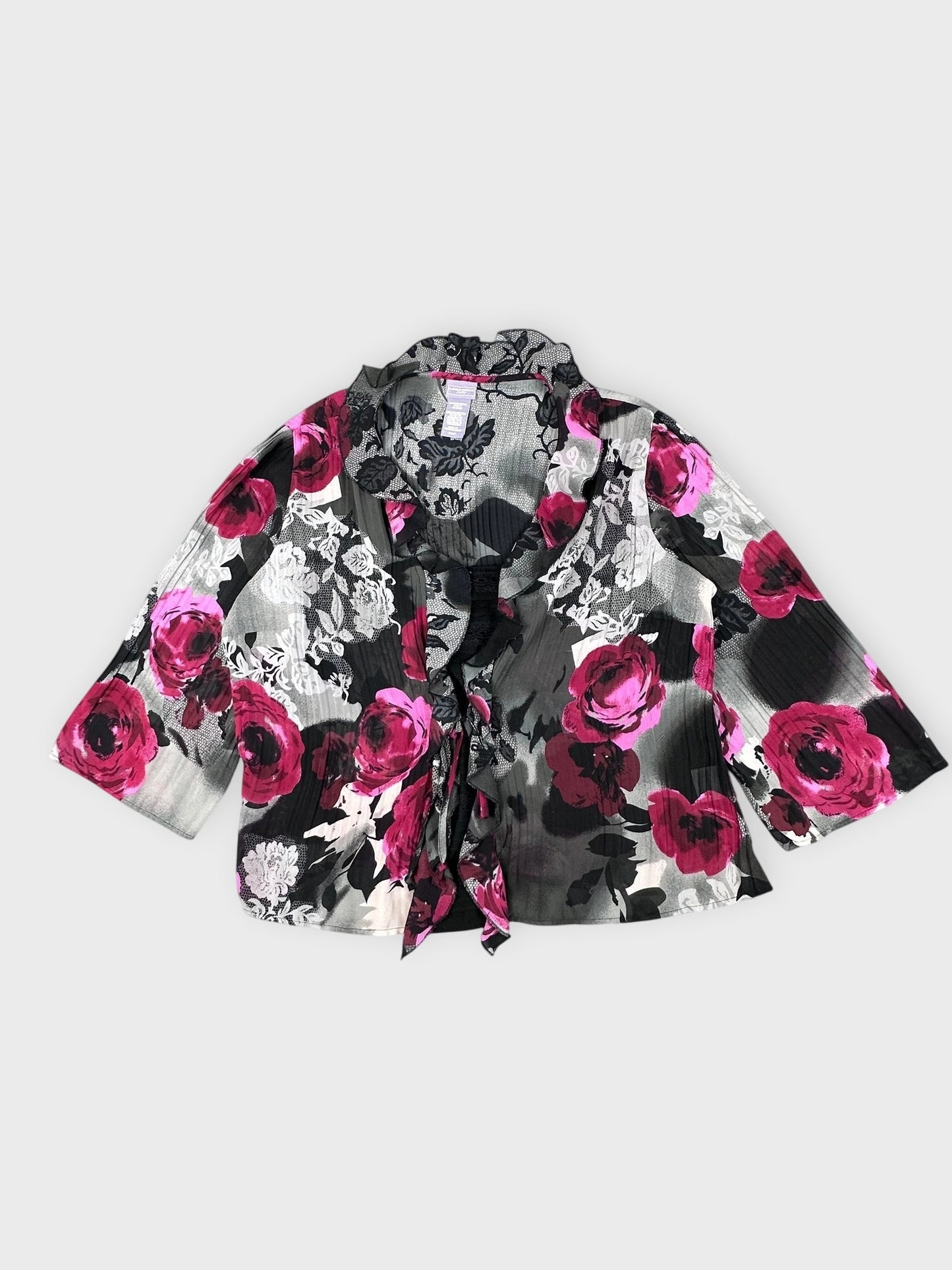 Detail view of a black blouse with pink floral pattern and ruffled collar