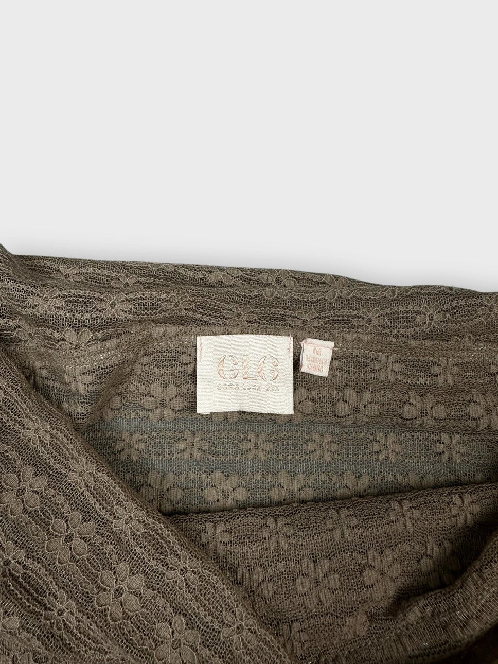 Detail view of brown long sleeve sheer top with floral texture.