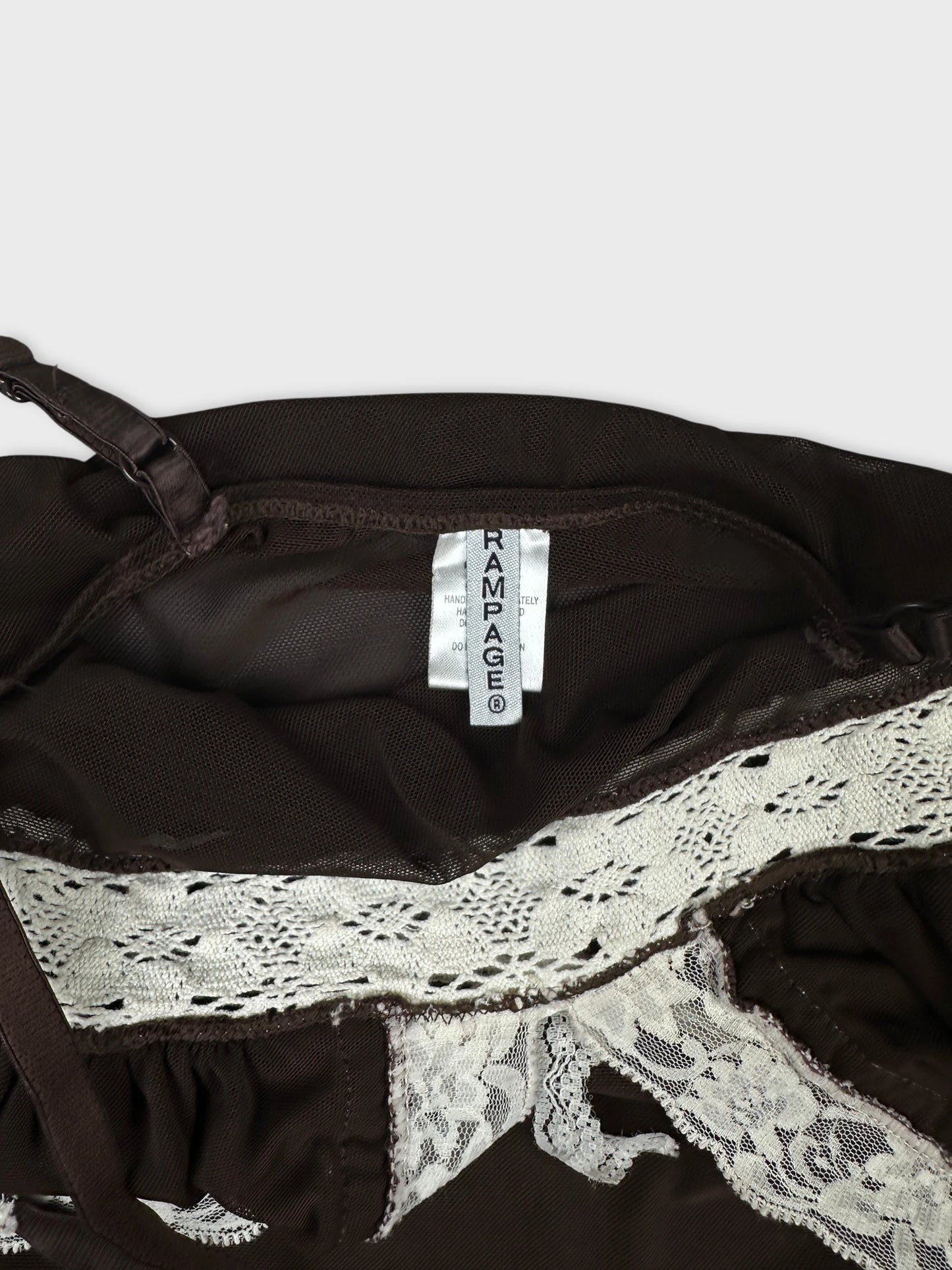 Detail view of brown mesh crop top featuring white lace trim.