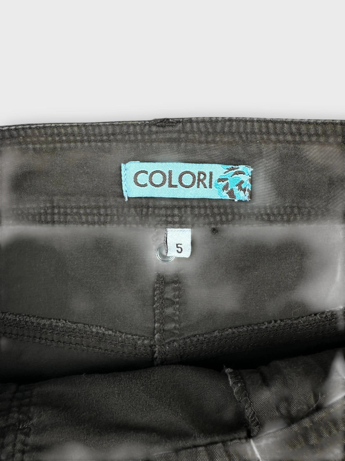 Detail view of brown mini skirt featuring side drawstrings and a visible brand tag.