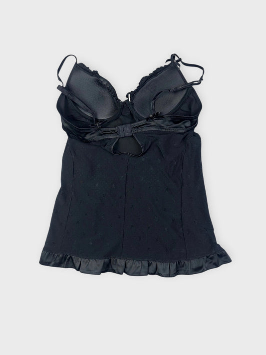 Back view of a black camisole featuring a ruffled hem.