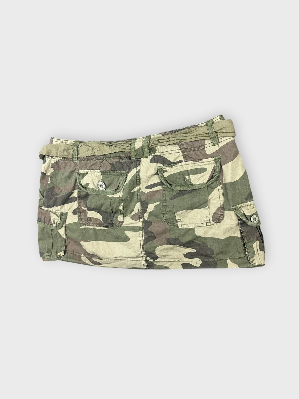 Detail view of a camo mini skirt with tie waist and pockets.