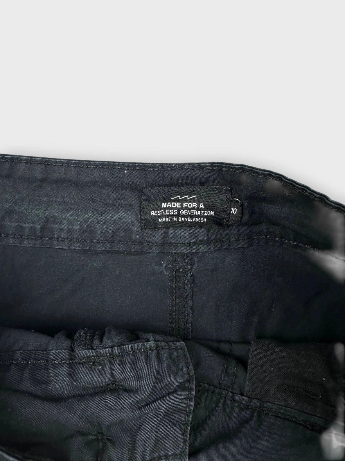 Detail view of a black mini skirt featuring visible inner waistband and lining.