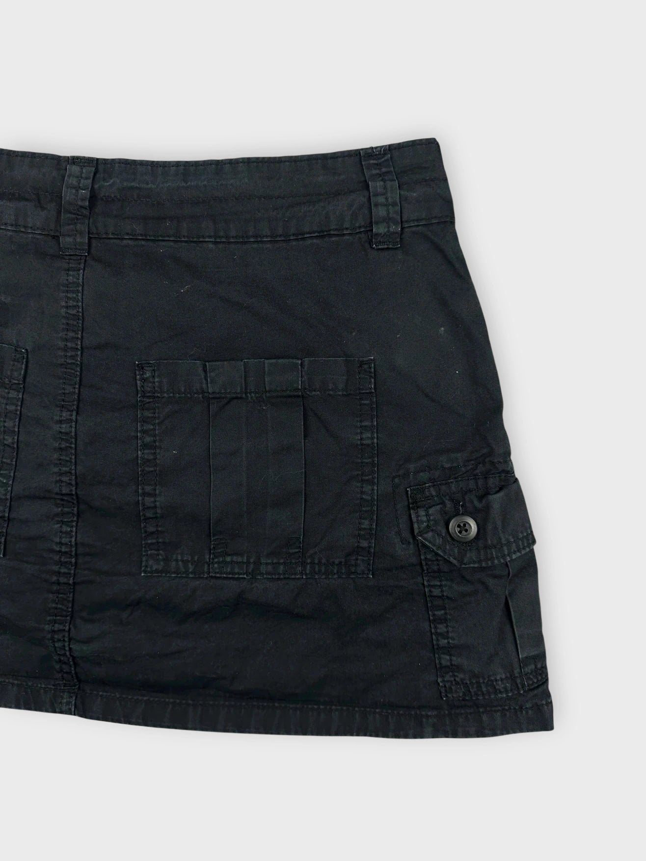 Detail view of a black mini skirt featuring front pockets and a relaxed fit.
