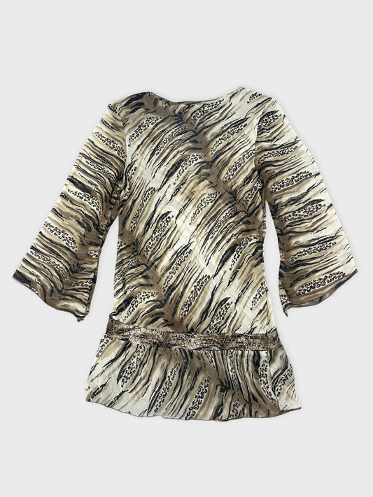 Back view of a beige animal print blouse featuring lace detail.