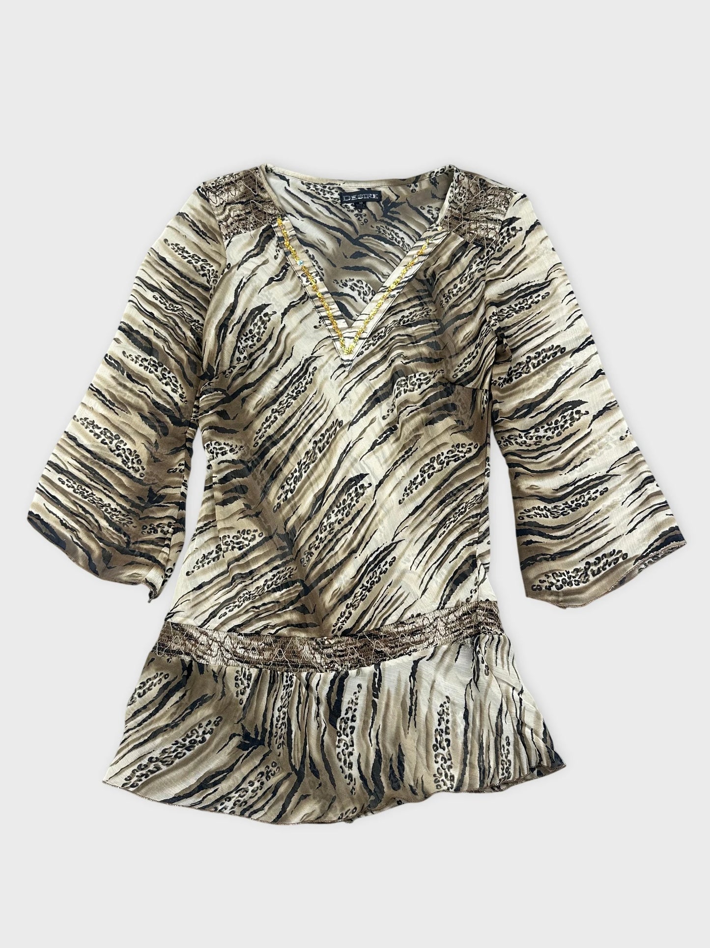 Detail view of a chic animal print blouse in beige with lace trim.