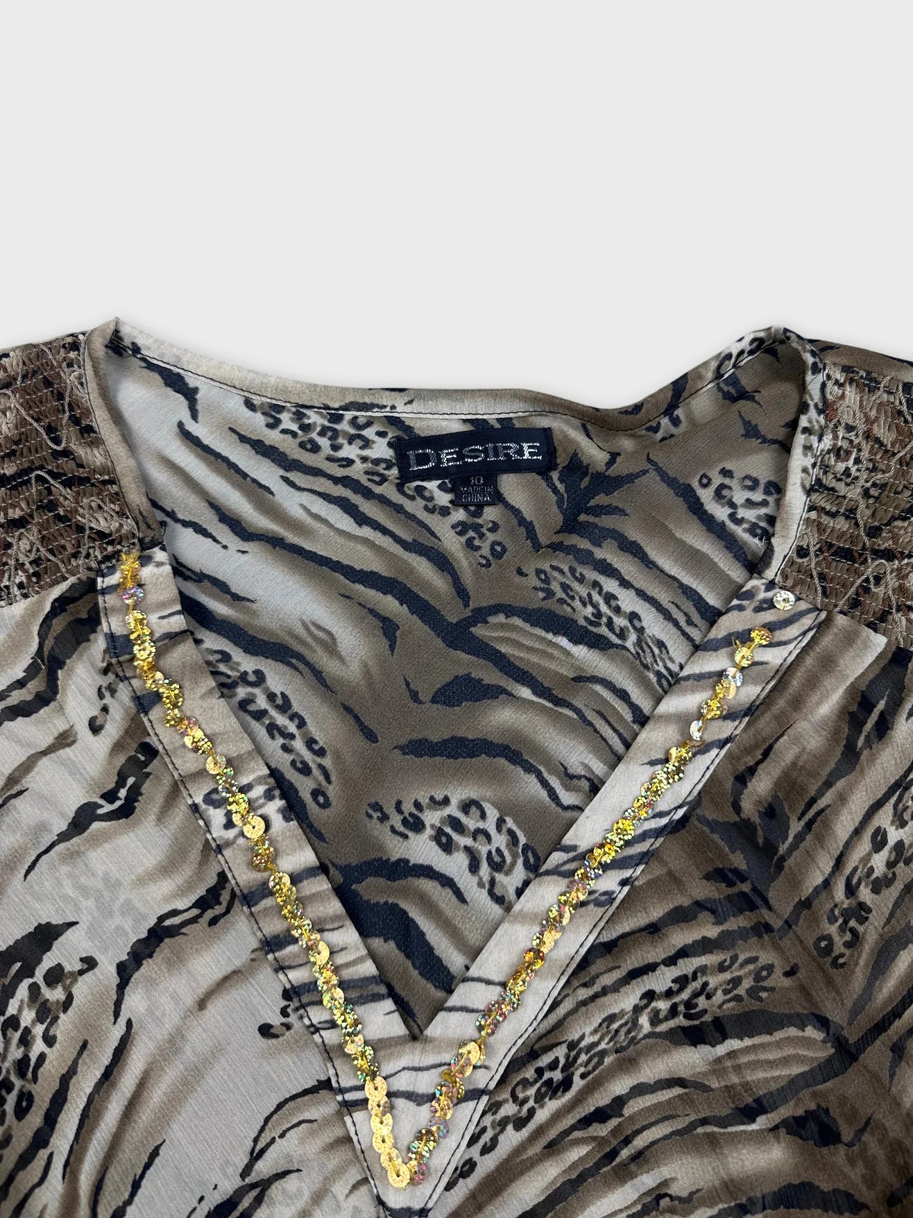 Detail view of a beige animal print blouse with lace trim and V-neck.